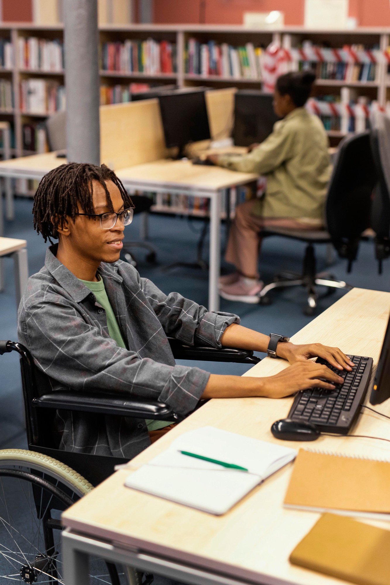 Un étudiant travaille sur son ordinateur en bibliothèque